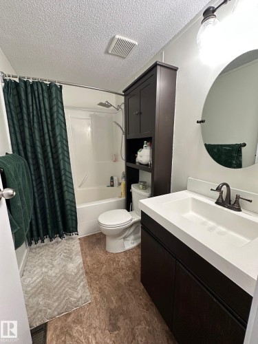 Bathroom with vanity, shower / bathtub combination with curtain, and a textured ceiling - 341 West Brook Way Nw, Edmonton, AB - Indoor Photo Showing Bathroom