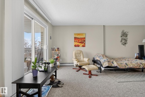 Carpeted bedroom featuring a textured ceiling and a baseboard heating unit - 302 4608 52 Avenue, Stony Plain, AB - Indoor