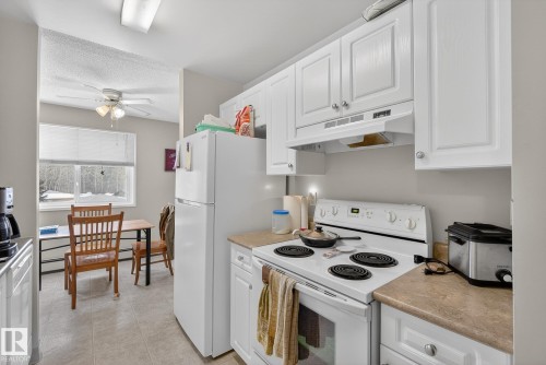 Kitchen with white range with electric cooktop, white cabinetry, light countertops, a ceiling fan, and a textured ceiling - 302 4608 52 Avenue, Stony Plain, AB - Indoor Photo Showing Kitchen