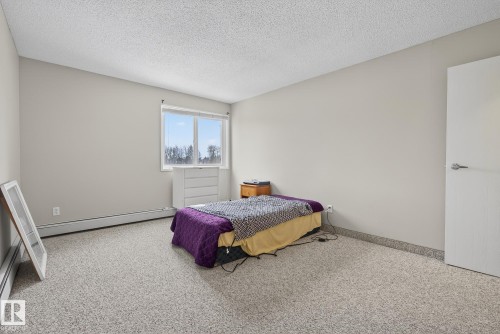 Bedroom featuring light colored carpet, a textured ceiling, and baseboard heating - 302 4608 52 Avenue, Stony Plain, AB - Indoor Photo Showing Bedroom