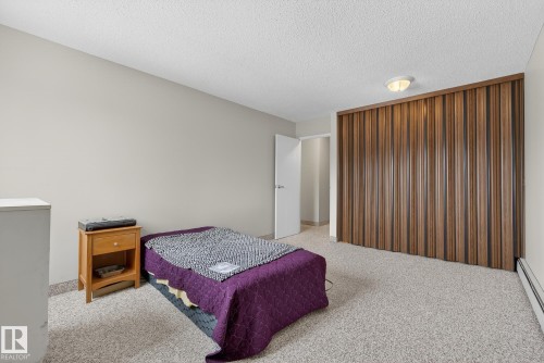 Bedroom featuring light colored carpet, a baseboard radiator, and a textured ceiling - 302 4608 52 Avenue, Stony Plain, AB - Indoor Photo Showing Bedroom