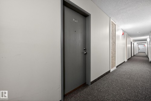 Hallway featuring dark carpet and a textured ceiling - 302 4608 52 Avenue, Stony Plain, AB - Indoor Photo Showing Other Room