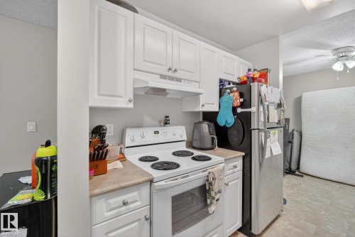 Kitchen with electric stove, white cabinetry, light countertops, a textured ceiling, and a ceiling fan - 307 4608 52 Avenue, Stony Plain, AB - Indoor Photo Showing Kitchen