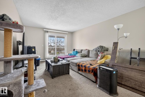 Living area featuring carpet floors and a textured ceiling - 307 4608 52 Avenue, Stony Plain, AB - Indoor Photo Showing Living Room