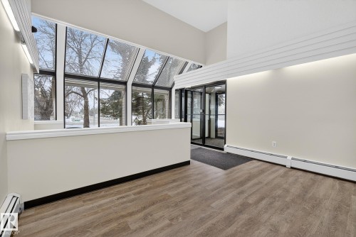 Unfurnished living room featuring baseboard heating and light wood-type flooring - 307 4608 52 Avenue, Stony Plain, AB - Indoor Photo Showing Other Room