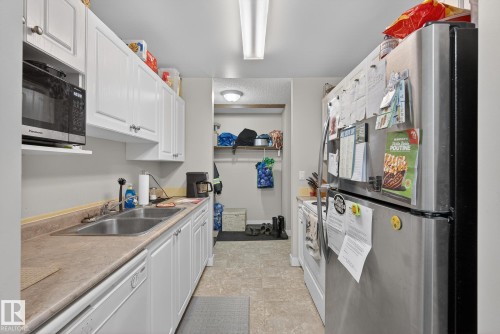 Kitchen featuring stainless steel appliances, white cabinetry, light countertops, and stone finish flooring - 307 4608 52 Avenue, Stony Plain, AB - Indoor Photo Showing Kitchen With Double Sink