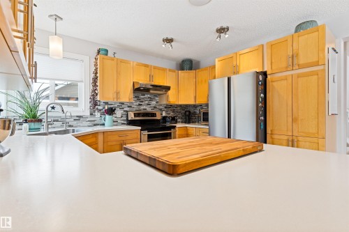 Kitchen with light countertops, stainless steel appliances, decorative backsplash, pendant lighting, and light wood finish cabinets - 7804 Schmid Place, Edmonton, AB - Indoor Photo Showing Kitchen