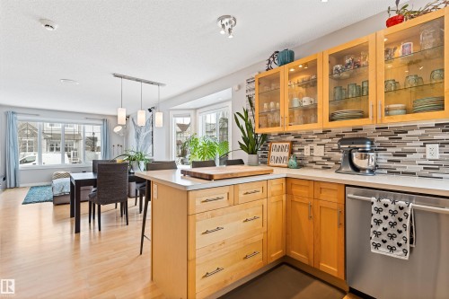 Kitchen featuring dishwasher, light countertops, a peninsula, glass fronted cabinets, and decorative backsplash - 7804 Schmid Place, Edmonton, AB - Indoor