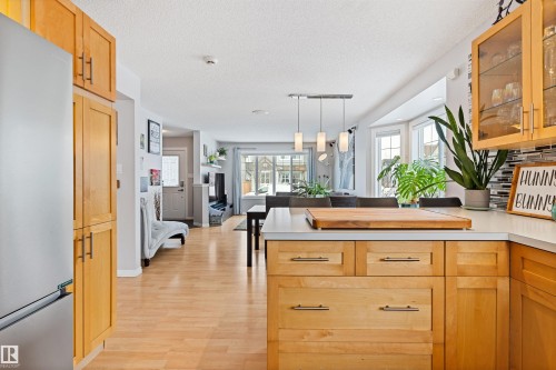 Kitchen featuring light countertops, glass insert cabinets, stainless steel fridge, pendant lighting, and a textured ceiling - 7804 Schmid Place, Edmonton, AB - Indoor Photo Showing Kitchen