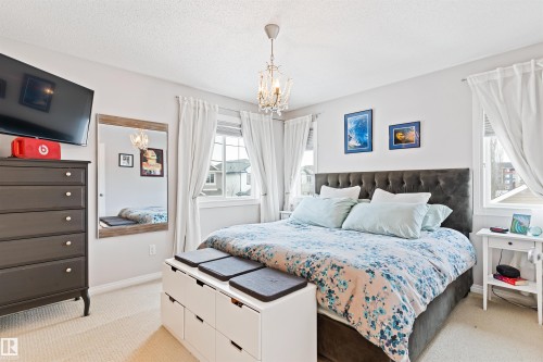 Bedroom featuring suspended lighting, light carpet, and a textured ceiling - 7804 Schmid Place, Edmonton, AB - Indoor Photo Showing Bedroom