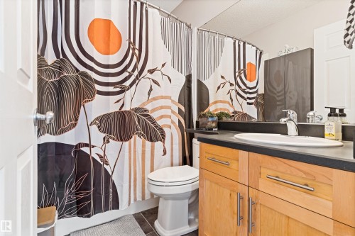 Bathroom featuring a shower with shower curtain, vanity, and dark tile patterned flooring - 7804 Schmid Place, Edmonton, AB - Indoor Photo Showing Bathroom