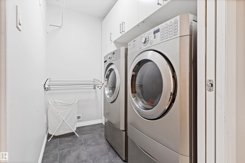Laundry room with independent washer and dryer, dark tile patterned flooring, and cabinet space - 7804 Schmid Place, Edmonton, AB - Indoor Photo Showing Laundry Room