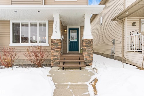Snow covered property entrance featuring covered porch and stone siding - 7804 Schmid Place, Edmonton, AB - 