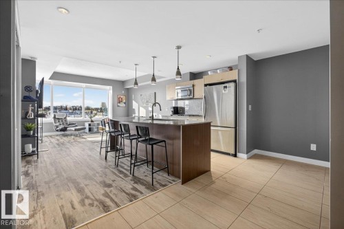 Kitchen featuring stainless steel appliances, a kitchen breakfast bar, pendant lighting, a kitchen island with sink, and dark stone countertops - 301 2504 109 Street, Edmonton, AB - Indoor Photo Showing Kitchen With Upgraded Kitchen