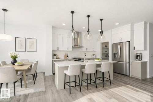 Kitchen featuring stainless steel appliances, a kitchen bar, light wood finished floors, white cabinetry, and a kitchen island with sink - 3790 Wren Loop, Edmonton, AB - Indoor