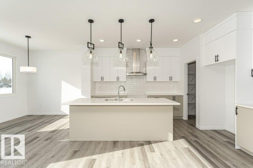 Kitchen featuring white cabinetry, a kitchen island with sink, light wood-style flooring, and hanging light fixtures - 3790 Wren Loop, Edmonton, AB - Indoor Photo Showing Kitchen With Upgraded Kitchen