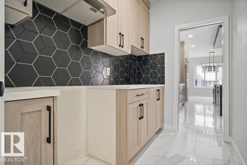 Kitchen with light wood finish cabinets, exhaust hood, light marble finish floors, recessed lighting, and backsplash - 3912 41 Avenue, Beaumont, AB - Indoor Photo Showing Other Room