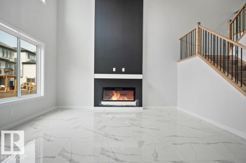 Unfurnished living room with light marble finish floors, a high ceiling, and a large fireplace - 3912 41 Avenue, Beaumont, AB - Indoor With Fireplace
