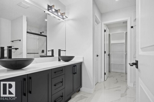 Bathroom with double vanity, a shower stall, light marble finish flooring, and a walk in closet - 3912 41 Avenue, Beaumont, AB - Indoor