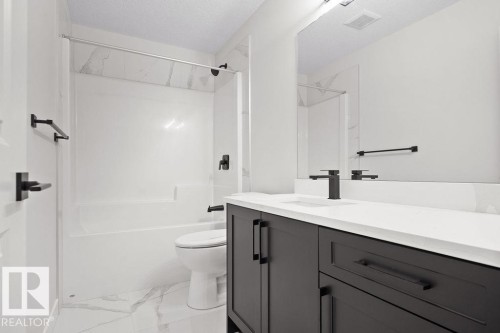 Full bathroom with vanity, a textured ceiling, tub / shower combination, and light marble finish floors - 3912 41 Avenue, Beaumont, AB - Indoor Photo Showing Bathroom