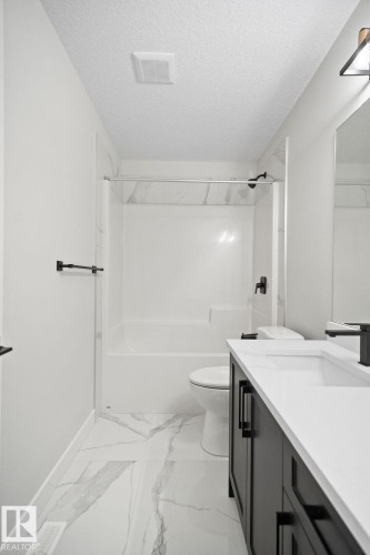 Full bathroom featuring vanity, a textured ceiling, shower / washtub combination, and light marble finish floors - 3912 41 Avenue, Beaumont, AB - Indoor Photo Showing Bathroom