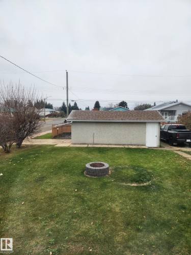 View of side of home with an outdoor fire pit and a lawn - 4505 57 Avenue, Barrhead, AB - Outdoor