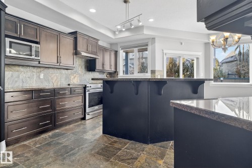 Kitchen with stainless steel appliances, tasteful backsplash, a breakfast bar area, and dark stone countertops - 613 Stewart Crescent, Edmonton, AB - Indoor Photo Showing Kitchen With Upgraded Kitchen