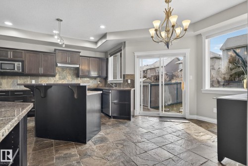Kitchen featuring tasteful backsplash, a breakfast bar, a kitchen island, stone tile flooring, and plenty of natural light - 613 Stewart Crescent, Edmonton, AB - Indoor Photo Showing Kitchen With Upgraded Kitchen