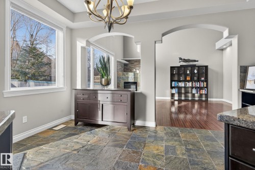 Bar area featuring a chandelier, stone tile flooring, arched walkways, dark wood finish cabinetry, and a tiled fireplace - 613 Stewart Crescent, Edmonton, AB - Indoor