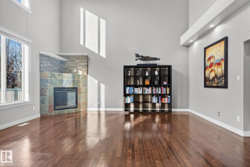 Living area featuring a high ceiling, dark wood-type flooring, a glass covered fireplace, and plenty of natural light - 613 Stewart Crescent, Edmonton, AB - Indoor With Fireplace