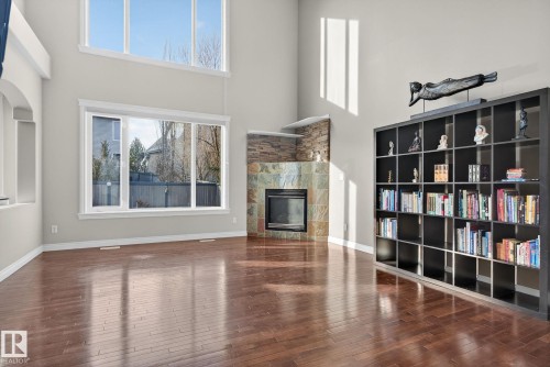 Unfurnished living room featuring dark wood finished floors, a fireplace, and a high ceiling - 613 Stewart Crescent, Edmonton, AB - Indoor Photo Showing Other Room With Fireplace