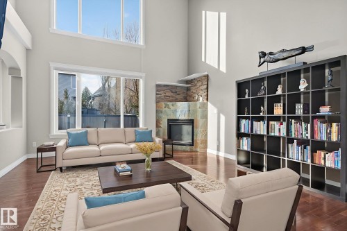 Living area with dark wood-style flooring, a fireplace, and a high ceiling - 613 Stewart Crescent, Edmonton, AB - Indoor Photo Showing Living Room With Fireplace