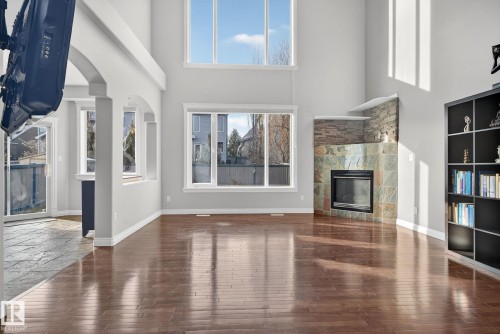 Unfurnished living room with a high ceiling, a glass covered fireplace, arched walkways, and dark wood finished floors - 613 Stewart Crescent, Edmonton, AB - Indoor With Fireplace