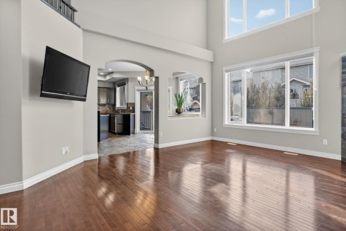 Unfurnished living room featuring arched walkways, a high ceiling, a chandelier, and dark wood finished floors - 613 Stewart Crescent, Edmonton, AB - Indoor Photo Showing Other Room