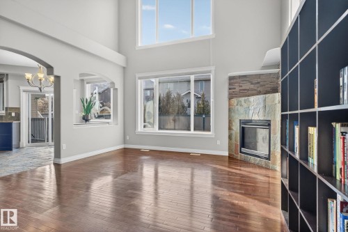 Unfurnished living room with a tile fireplace, arched walkways, dark wood-style floors, a high ceiling, and hanging lights - 613 Stewart Crescent, Edmonton, AB - Indoor Photo Showing Other Room