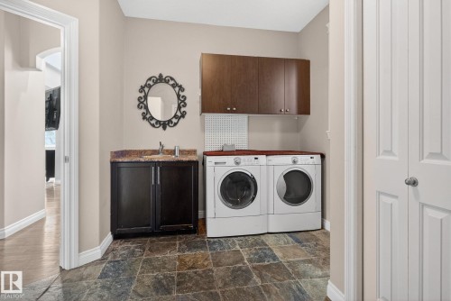 Laundry room with cabinet space, dark stone finish flooring, and independent washer and dryer - 613 Stewart Crescent, Edmonton, AB - Indoor Photo Showing Laundry Room