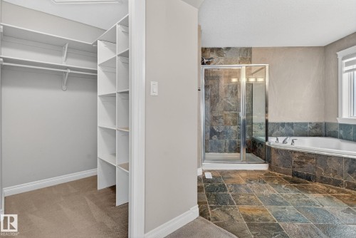 Bathroom with a walk in closet, a stall shower, stone tile floors, and a bath - 613 Stewart Crescent, Edmonton, AB - Indoor Photo Showing Bathroom