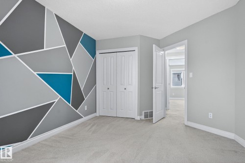 Unfurnished bedroom featuring an accent wall, light colored carpet, and a closet - 613 Stewart Crescent, Edmonton, AB - Indoor Photo Showing Other Room