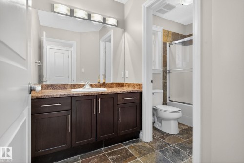 Full bath with vanity, enclosed tub / shower combo, and dark stone finish flooring - 613 Stewart Crescent, Edmonton, AB - Indoor Photo Showing Bathroom