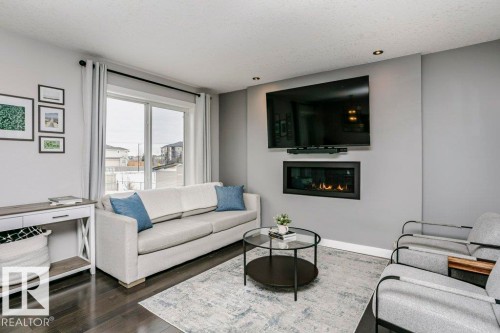 Living area featuring a glass covered fireplace, dark wood-type flooring, and a textured ceiling - 6710 Cardinal Road, Edmonton, AB - Indoor Photo Showing Living Room