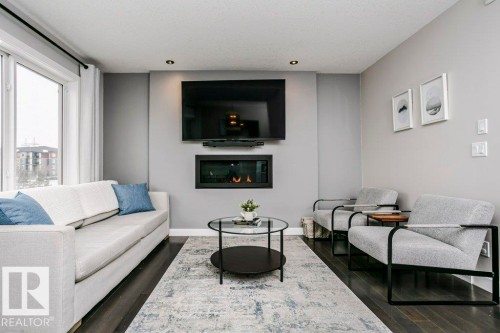 Living room featuring a glass covered fireplace and dark wood finished floors - 6710 Cardinal Road, Edmonton, AB - Indoor Photo Showing Living Room