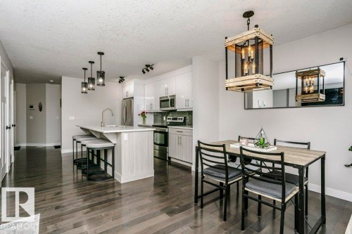 Kitchen with stainless steel appliances, tasteful backsplash, a breakfast bar, white cabinetry, and a center island with sink - 6710 Cardinal Road, Edmonton, AB - Indoor Photo Showing Dining Room