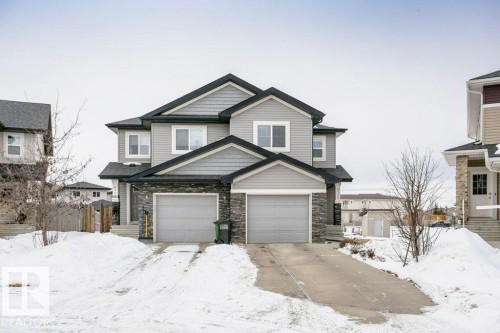 Craftsman-style home featuring stone siding, an attached garage, and driveway - 6710 Cardinal Road, Edmonton, AB - Outdoor With Facade