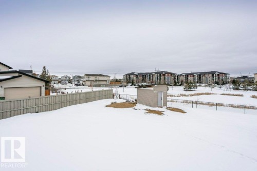 Snowy yard featuring a residential view, a fenced backyard, and a shed - 6710 Cardinal Road, Edmonton, AB - Outdoor With View