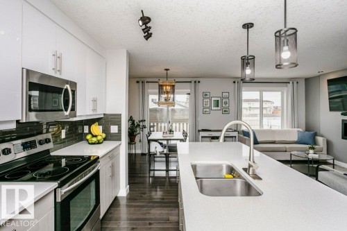 Kitchen with stainless steel appliances, dark wood finished floors, backsplash, a textured ceiling, and white cabinetry - 6710 Cardinal Road, Edmonton, AB - Indoor Photo Showing Kitchen With Stainless Steel Kitchen With Double Sink With Upgraded Kitchen