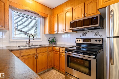 Kitchen with stainless steel appliances, tasteful backsplash, and wood finish cabinets - 13420 113A St, Edmonton, AB - Indoor Photo Showing Kitchen With Double Sink