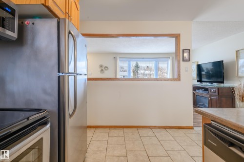 Kitchen featuring stainless steel appliances, light tile patterned flooring, and wood finish cabinets - 13420 113A St, Edmonton, AB - Indoor Photo Showing Kitchen