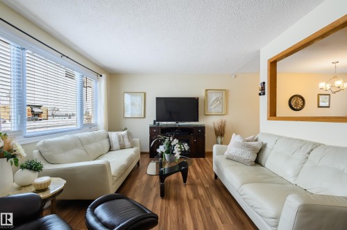 Living area with wood finished floors, hanging lights, and a textured ceiling - 13420 113A St, Edmonton, AB - Indoor Photo Showing Living Room