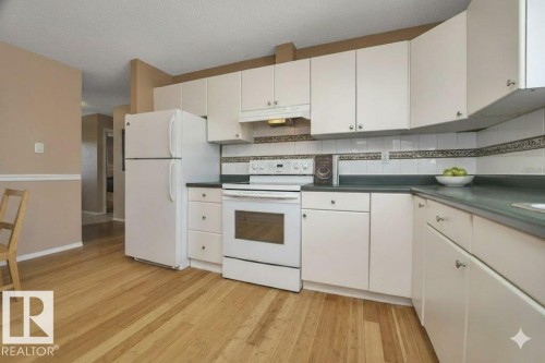 Kitchen featuring white appliances, tasteful backsplash, light wood-style flooring, white cabinets, and a textured ceiling - 4406 39 Ave, Leduc, AB - Indoor Photo Showing Kitchen