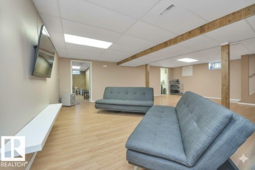 Living room featuring light wood finished floors and a drop ceiling - 4406 39 Ave, Leduc, AB - Indoor Photo Showing Basement